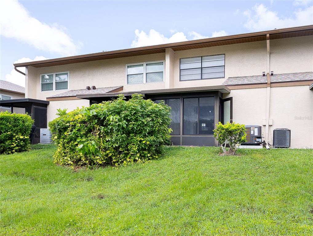 The rear exterior of a two-story townhouse features a screened-in patio and a grassy yard — 9209 SEMINOLE BOULEVARD UNIT 79, SEMINOLE, FL