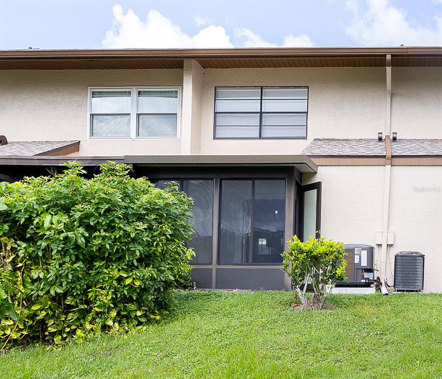 A two-story building exterior features a screened-in patio, a large bush, and two air-conditioning units — 9209 SEMINOLE BOULEVARD UNIT 79, SEMINOLE, FL