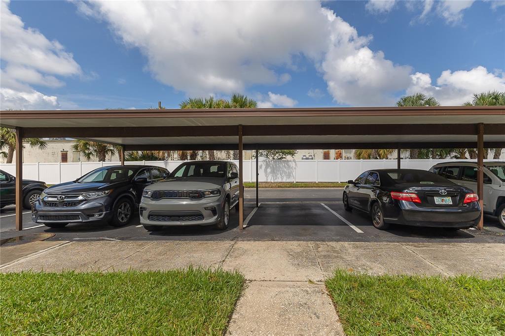 A covered parking area with four designated spaces and three parked vehicles — 9209 SEMINOLE BOULEVARD UNIT 79, SEMINOLE, FL