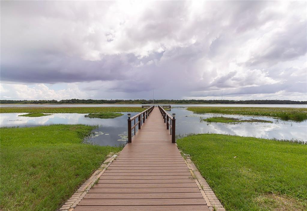 A wooden pier extends over a grassy lakefront area under a cloudy sky — 9209 SEMINOLE BOULEVARD UNIT 79, SEMINOLE, FL