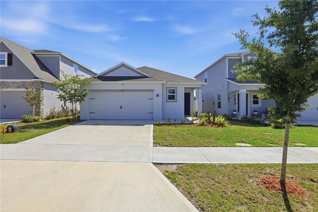 A single-story house with a white exterior, a two-car garage, and a concrete driveway — 4057 SAGEFIELD DRIVE, HARMONY, FL