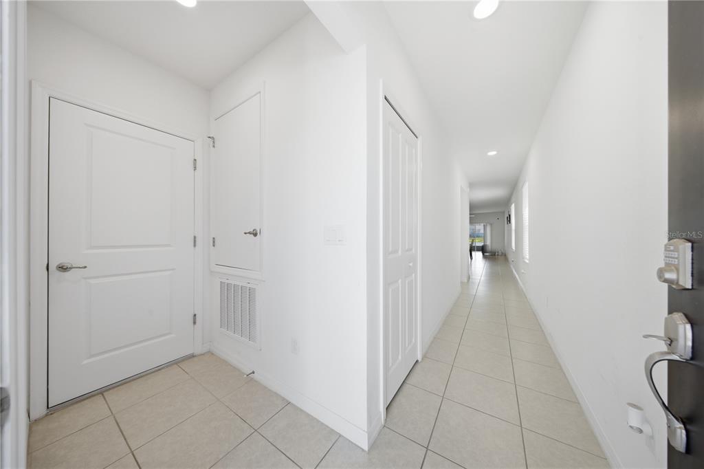 A bright entryway with tiled floors leads into a long hallway with white walls — 4057 SAGEFIELD DRIVE, HARMONY, FL