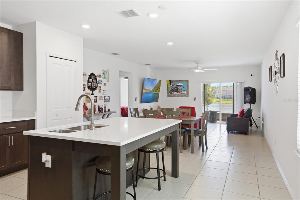A kitchen island with a sink overlooks an open-concept dining area and living space — 4057 SAGEFIELD DRIVE, HARMONY, FL