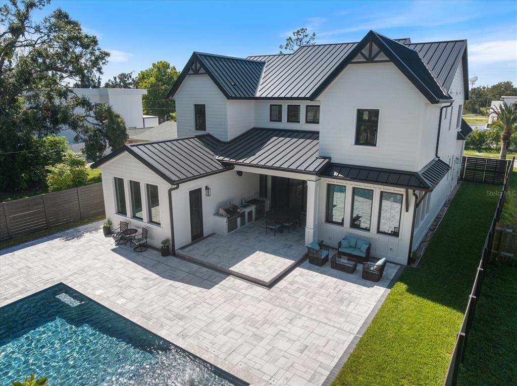 A two-story modern farmhouse with white vertical siding, a dark metal roof, and a driveway — 2045 GOLDENROD STREET, SARASOTA, FL