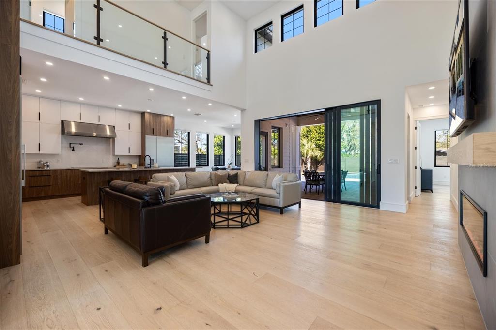 A bright, modern foyer features light wood floors, a glass-railed staircase, and white walls — 2045 GOLDENROD STREET, SARASOTA, FL