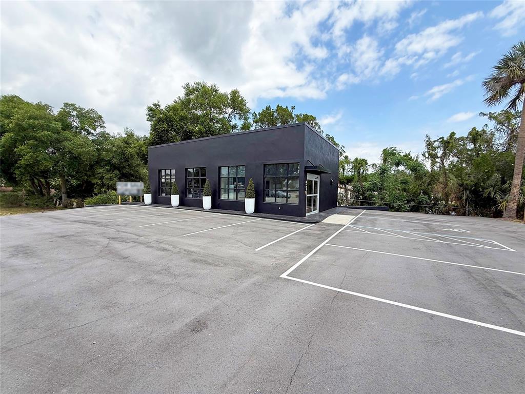 A black, flat-roofed commercial building sits behind a large, empty asphalt parking lot — 516 E HIGHWAY 50, CLERMONT, FL