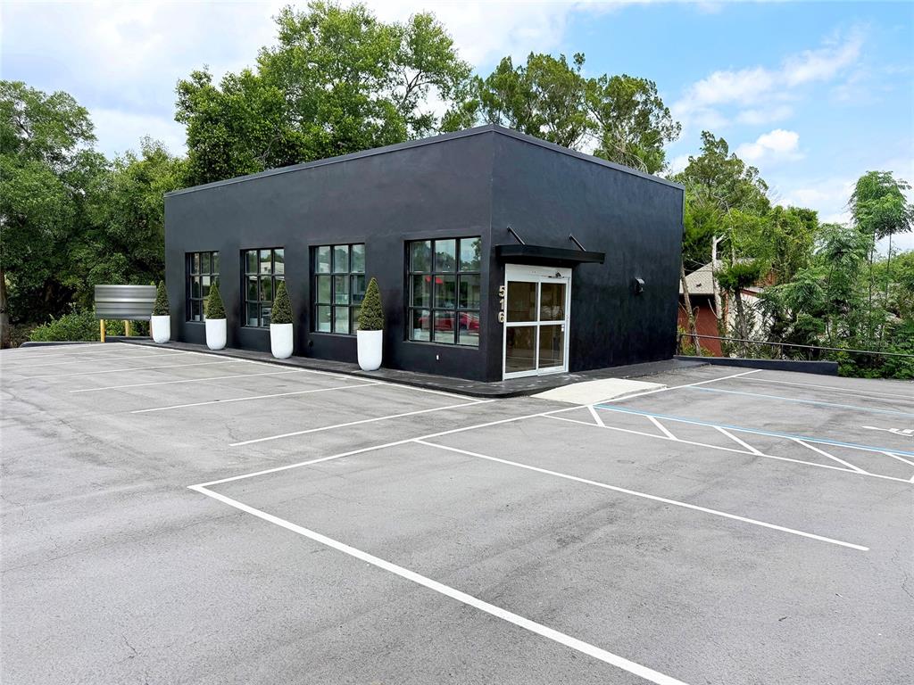 A modern, flat-roofed black commercial building features large windows and a paved parking lot — 516 E HIGHWAY 50, CLERMONT, FL