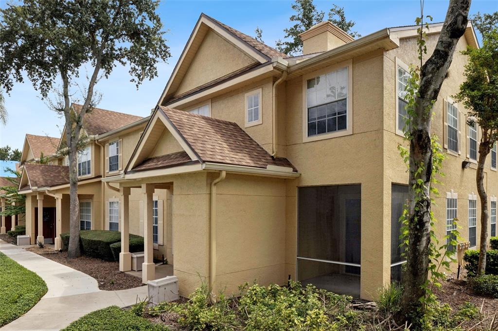 A two-story tan stucco townhouse with a brown shingled roof and a screened-in porch — 832 GRAND REGENCY POINTE POINT UNIT 105, ALTAMONTE SPRINGS, FL