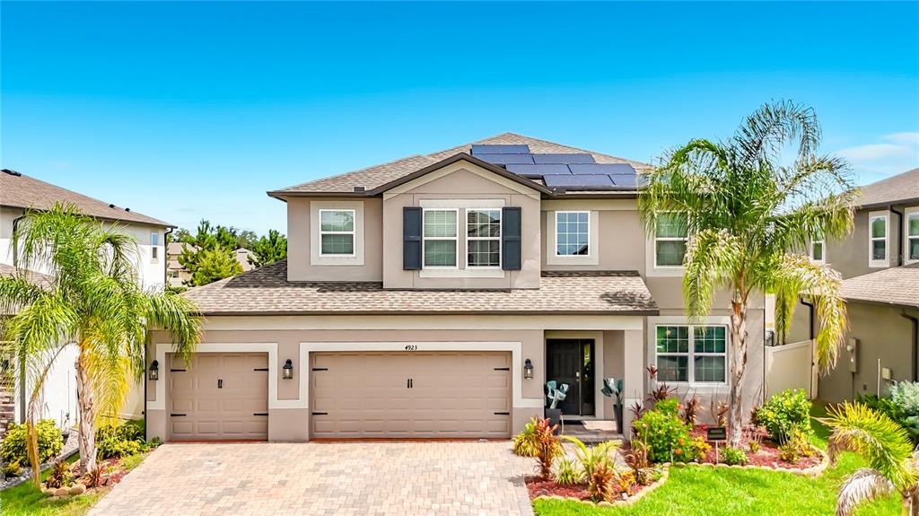 A two-story suburban house with a three-car garage, solar panels, and palm trees — 4923 EAGLE ROCK DRIVE, WIMAUMA, FL