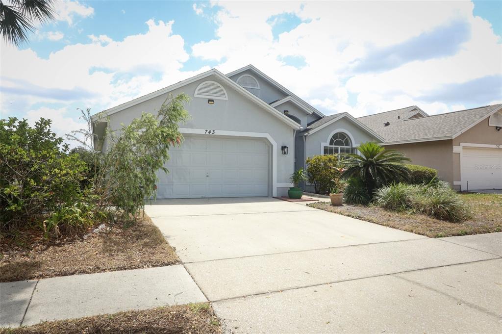 A single-story house with a two-car garage, light-colored stucco siding, and a concrete driveway — 743 DEACON WINN COURT, ORLANDO, FL