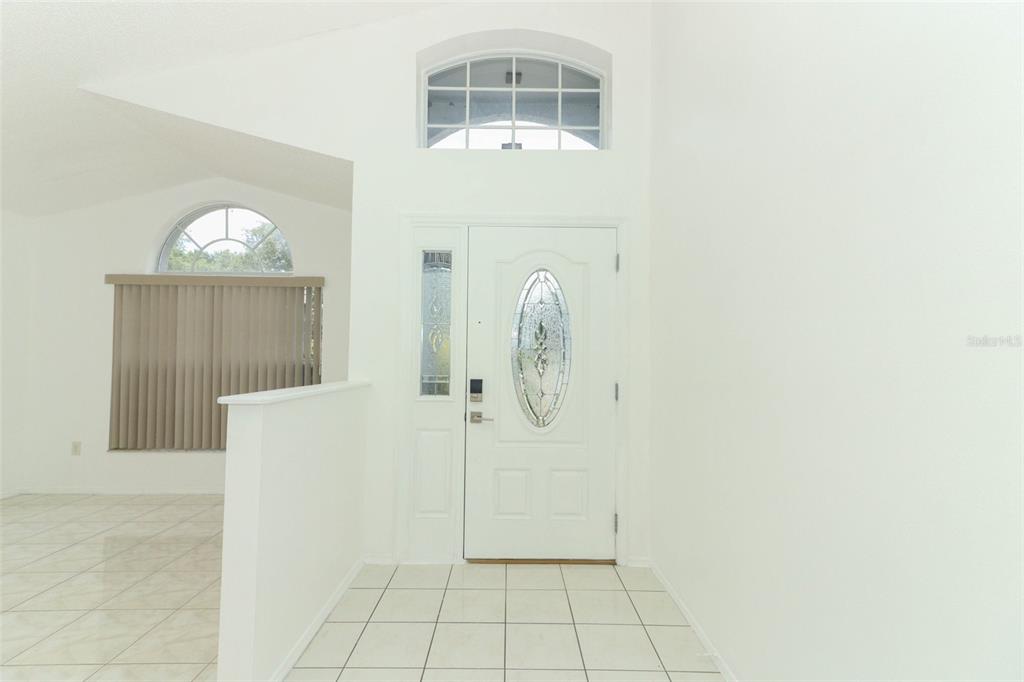 An entryway with white tile floors, a white front door, and a high vaulted ceiling — 743 DEACON WINN COURT, ORLANDO, FL