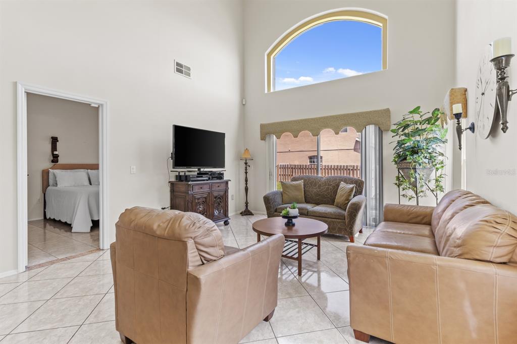 A living room with high ceilings, tile floors, a television, and leather seating furniture — 13037 LILY POND COURT, ORLANDO, FL