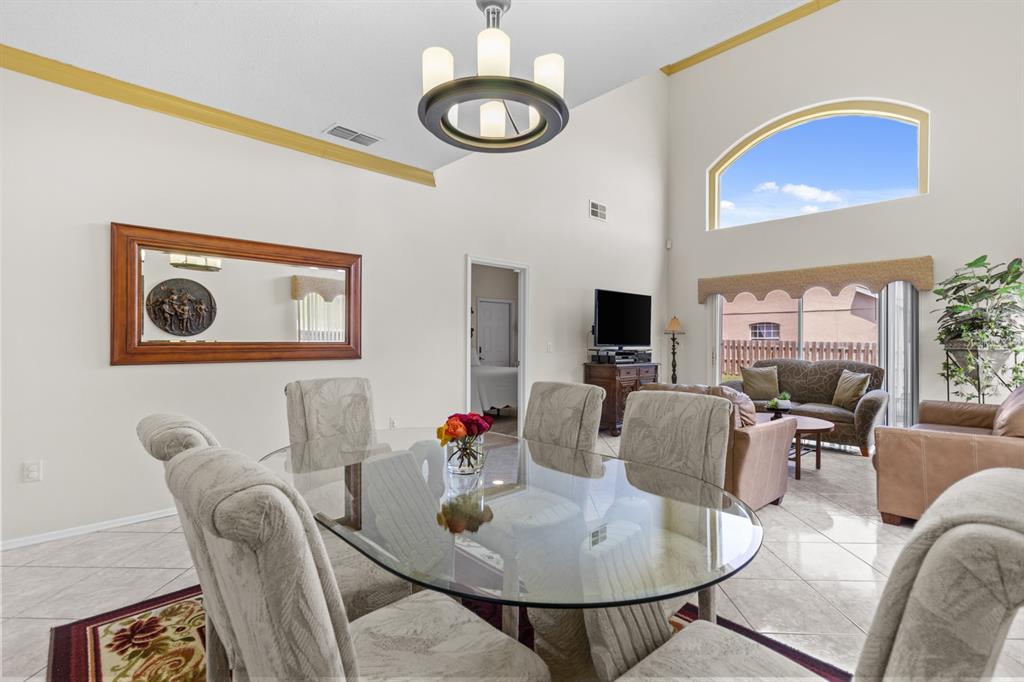 A dining area with a glass table and chairs sits before a living room space — 13037 LILY POND COURT, ORLANDO, FL