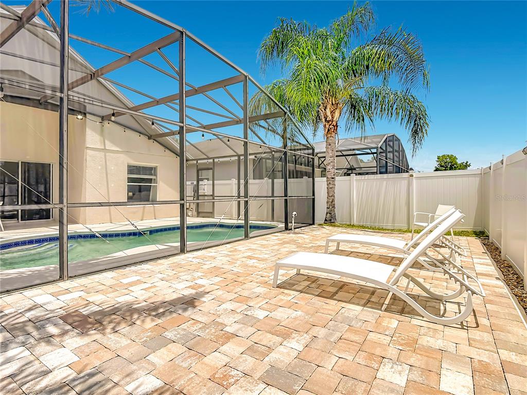 A dining area with a glass table and chairs sits adjacent to a modern kitchen — 1021 TOURMALINE DRIVE, KISSIMMEE, FL