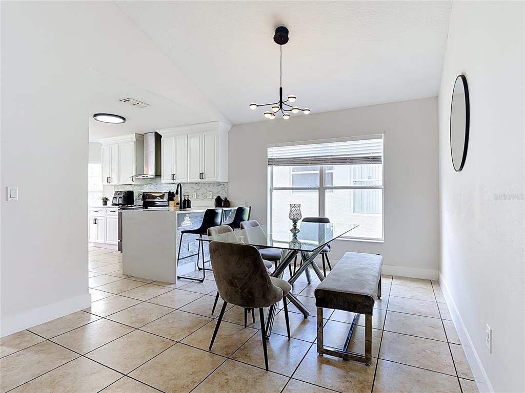 A living room features tile floors, a vaulted ceiling, a sofa, and a sliding glass door — 1021 TOURMALINE DRIVE, KISSIMMEE, FL