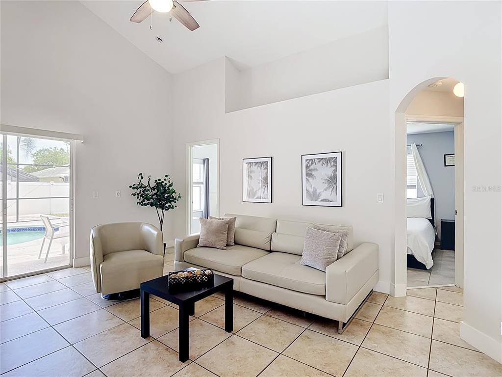 A screened-in swimming pool with a patio and white vinyl fencing in a backyard — 1021 TOURMALINE DRIVE, KISSIMMEE, FL