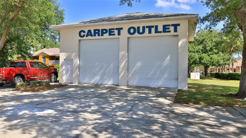 A beige commercial building with two roll-up garage doors and a red pickup truck parked — 4720 E MOODY BOULEVARD, BUNNELL, FL