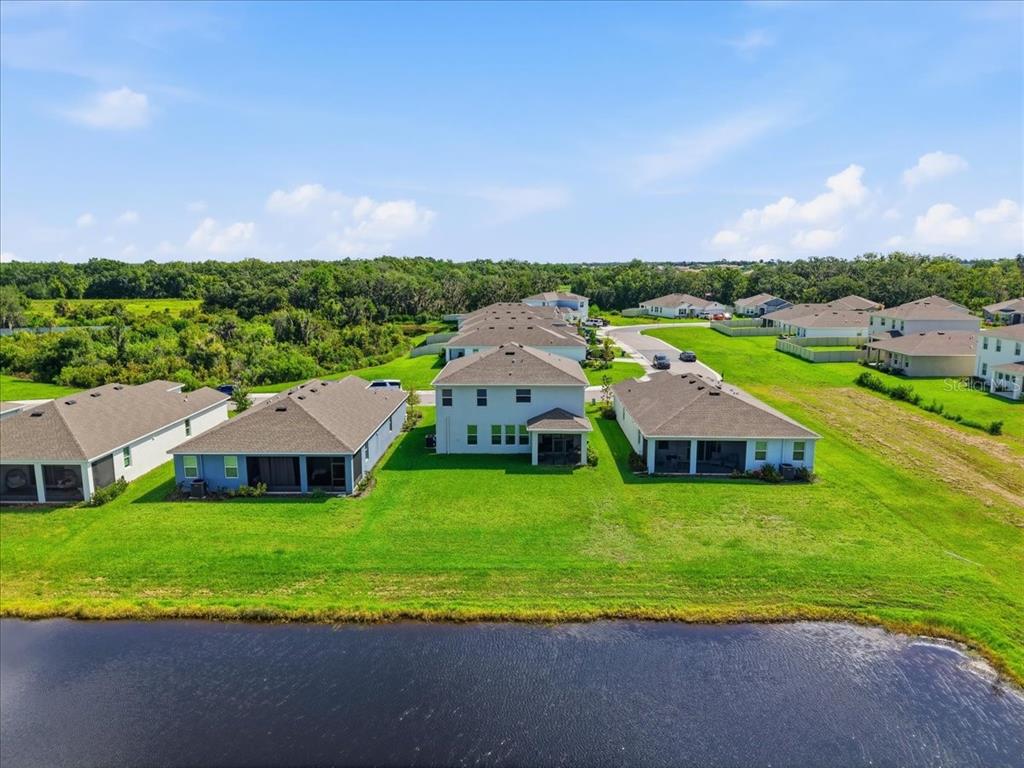 An aerial view of several suburban houses with backyards facing a pond and wooded area — 16018 6TH AVENUE E, BRADENTON, FL