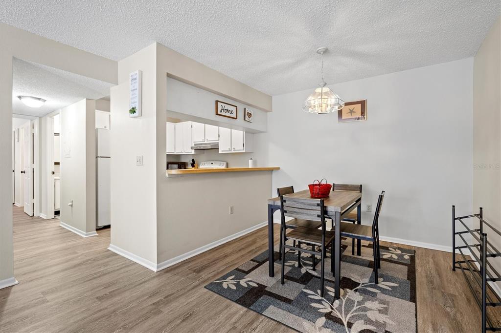 A dining area with a wooden table, chairs, area rug, and a kitchen pass-through window — 3275 BENEVA ROAD UNIT 104, SARASOTA, FL