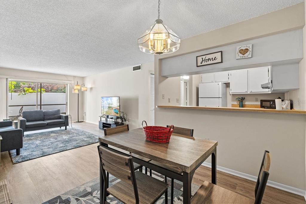 A dining area with a wood table overlooks a living room and an open kitchen — 3275 BENEVA ROAD UNIT 104, SARASOTA, FL