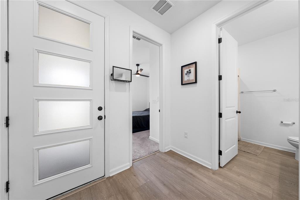 A white door, a doorway to a bedroom, and a bathroom entrance with wood flooring — 4035 SOUTHERN VISTA LOOP, ST CLOUD, FL