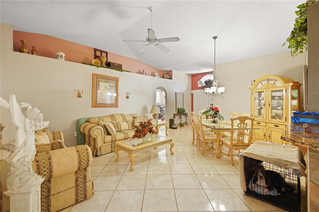 A kitchen with wood cabinets, granite countertops, and tile flooring opens to a dining area — 11545 BENTRY STREET, ORLANDO, FL