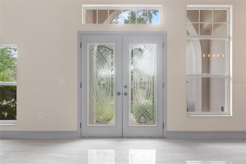 A light-colored entryway features double glass-paneled doors, a transom window, and large floor tiles — 10217 TIMBERLAND POINT DRIVE, TAMPA, FL