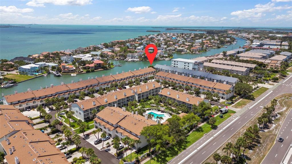 An aerial view shows a multi-story condominium complex with a pool near a waterway — 367 MADEIRA CIRCLE, TIERRA VERDE, FL