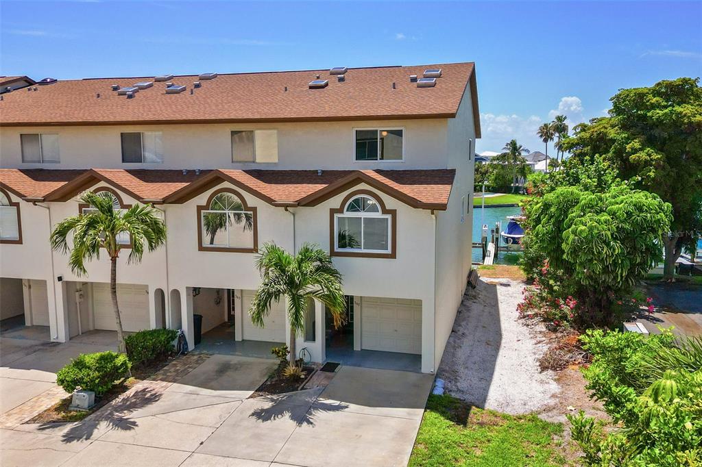 An exterior view of a multi-story townhouse with a garage and a nearby canal — 367 MADEIRA CIRCLE, TIERRA VERDE, FL