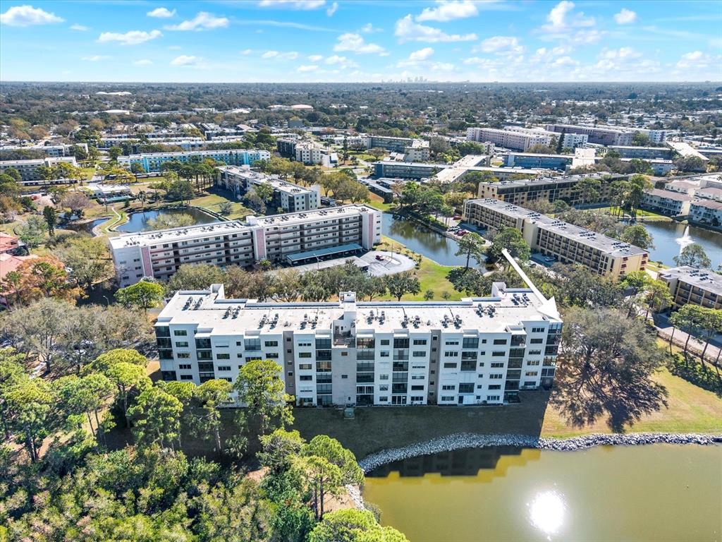 An aerial view shows a multi-story apartment building situated next to a small lake — 8186 TERRACE GARDEN DRIVE N UNIT 601, ST PETERSBURG, FL