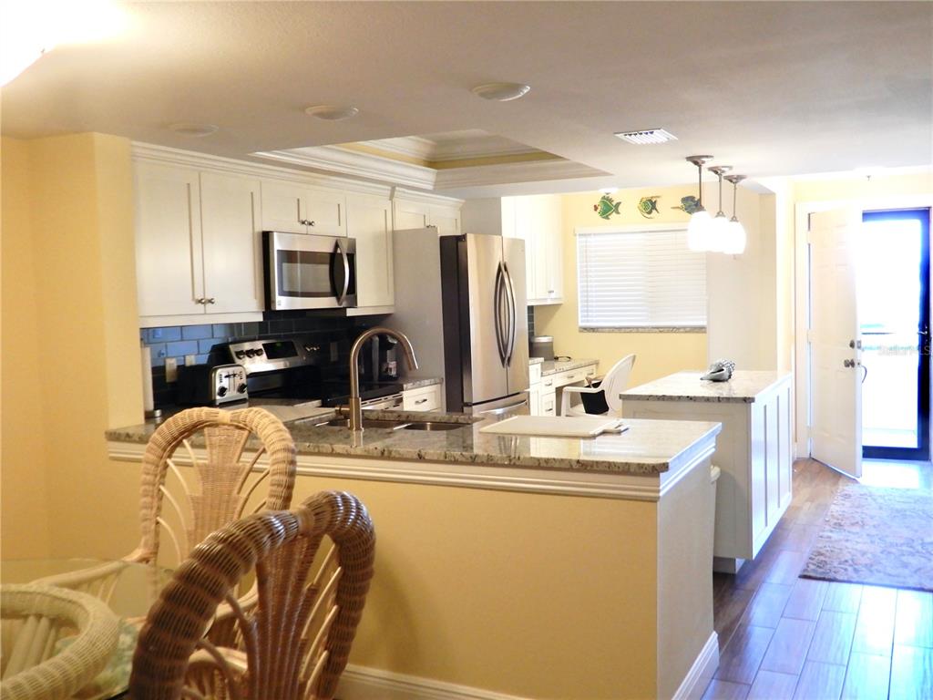 A kitchen with white cabinets, granite countertops, stainless steel appliances, and a central island — 103 1ST STREET E UNIT 210, TIERRA VERDE, FL