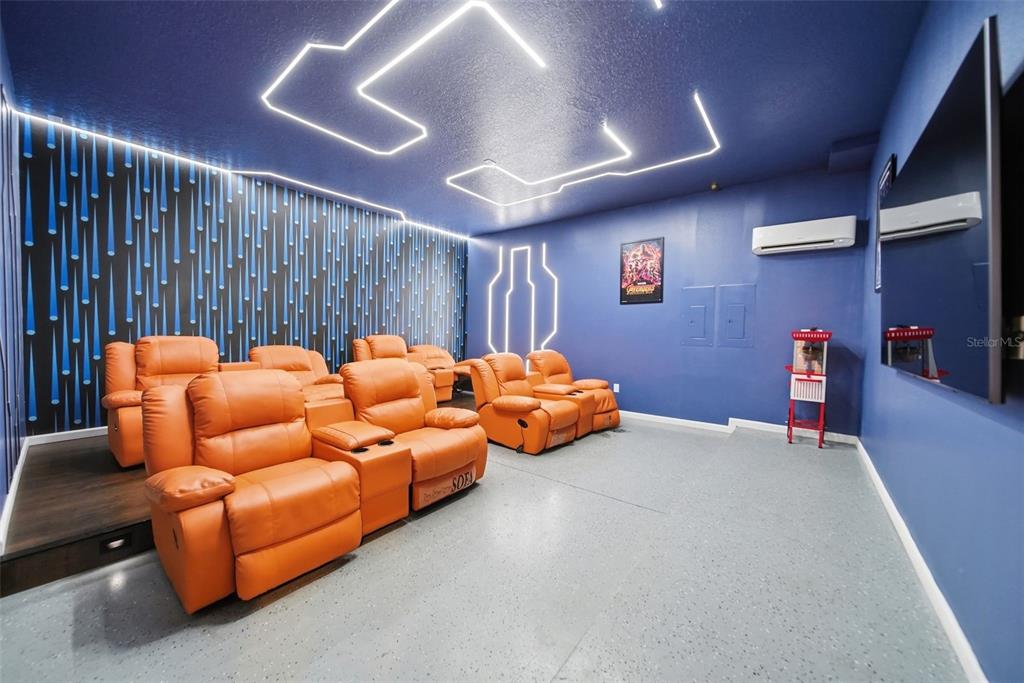 A home theater features orange reclining chairs, blue walls, neon ceiling lighting, and a popcorn machine — 2532 SHANTI DRIVE, KISSIMMEE, FL