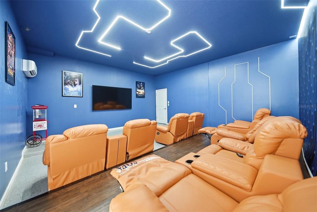 A home theater room features blue walls, orange reclining chairs, and geometric LED ceiling lighting — 2532 SHANTI DRIVE, KISSIMMEE, FL