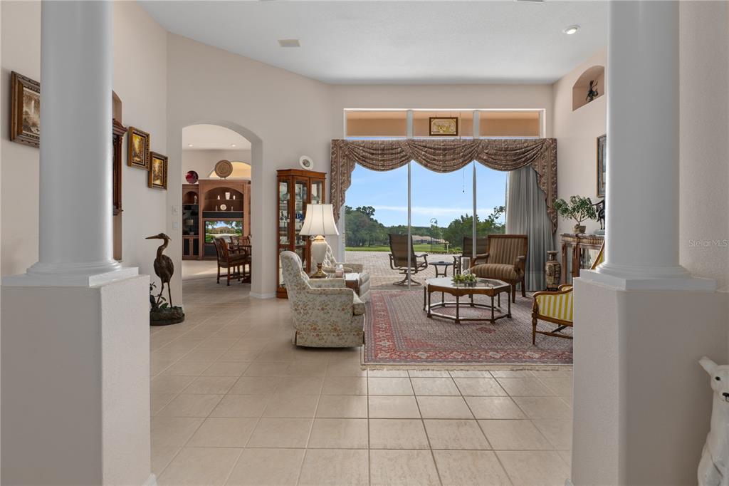 A living room with tile floors, columns, and large windows overlooking a patio and yard — 1969 N YAWKEY POINT, HERNANDO, FL