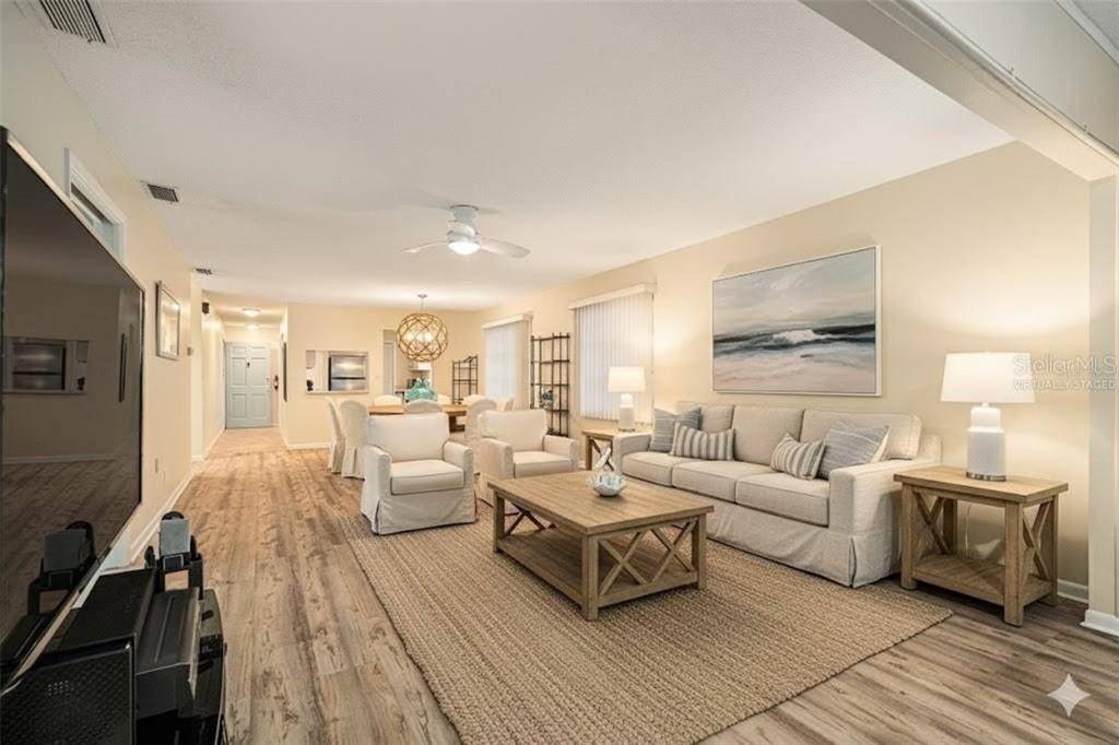 This living room features light wood-look flooring, a beige sofa, and a central coffee table — 11200 102ND AVENUE UNIT 16, SEMINOLE, FL