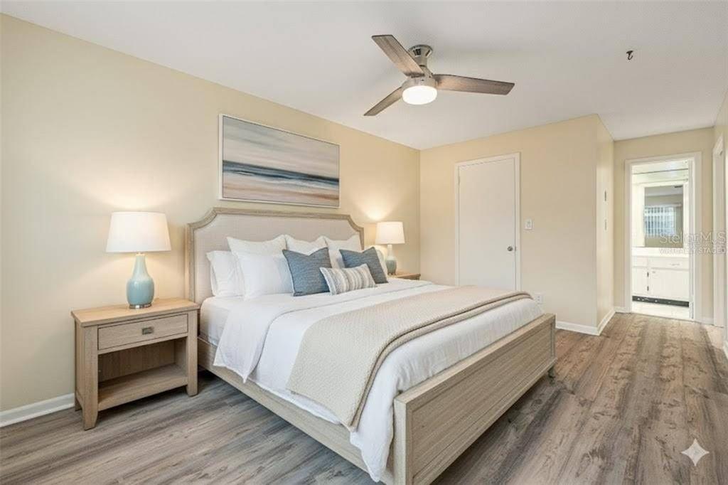 A bedroom with a bed, two nightstands, a ceiling fan, and light wood-look flooring — 11200 102ND AVENUE UNIT 16, SEMINOLE, FL