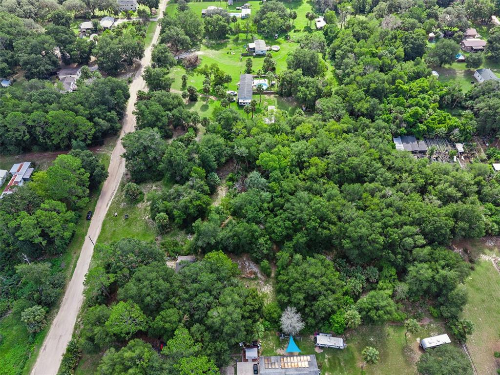 An aerial view shows a rural property with a dirt road, trees, and several buildings — 22308 HORIZON VISTAS DRIVE, EUSTIS, FL