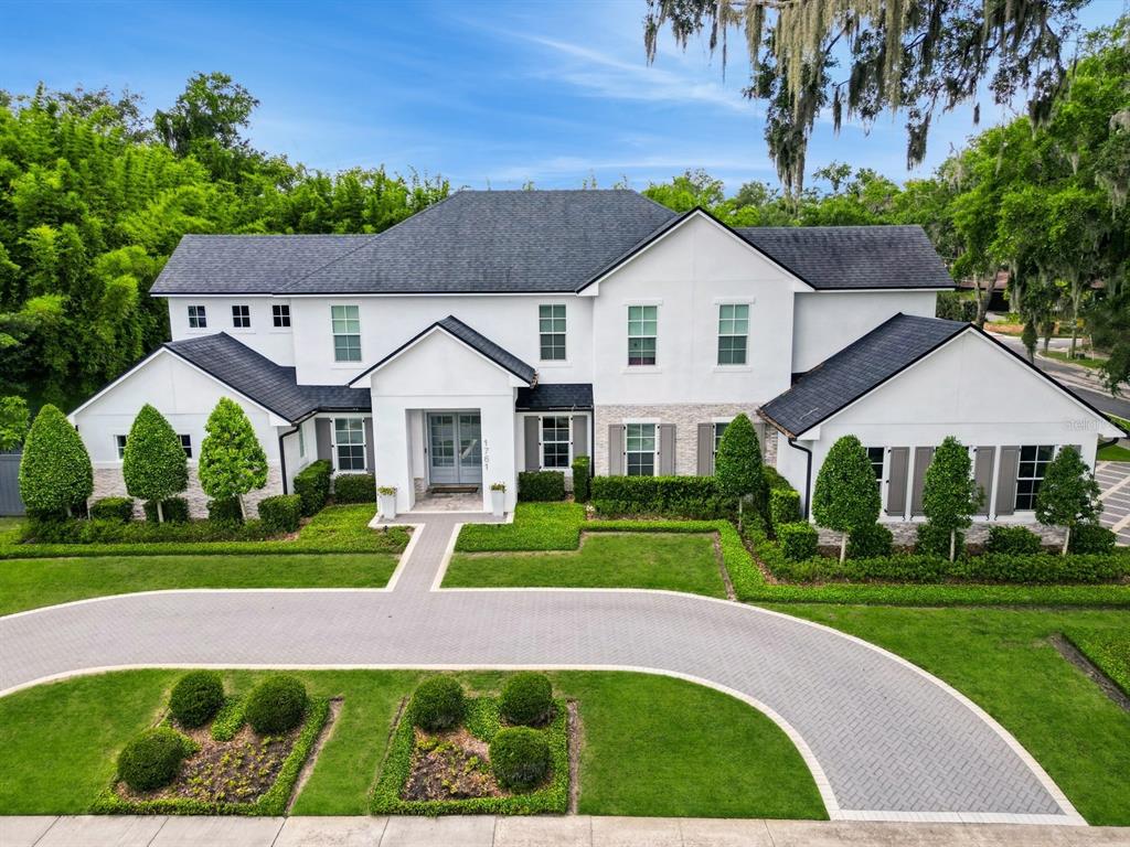 A two-story white house with a dark roof, stone accents, and a curved paver driveway — 1761 LEGION DRIVE, WINTER PARK, FL