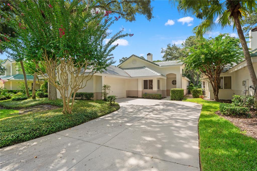 A single-story house with a concrete driveway, a two-car garage, and mature landscaping — 6005 FAIRWAY PALMS COURT, TAMPA, FL