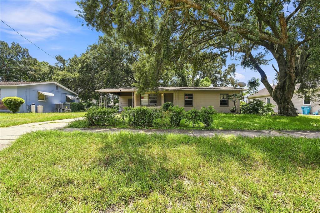 A single-story house with a carport and mature trees sits behind a grassy front yard — 4186 CEPEDA STREET, ORLANDO, FL