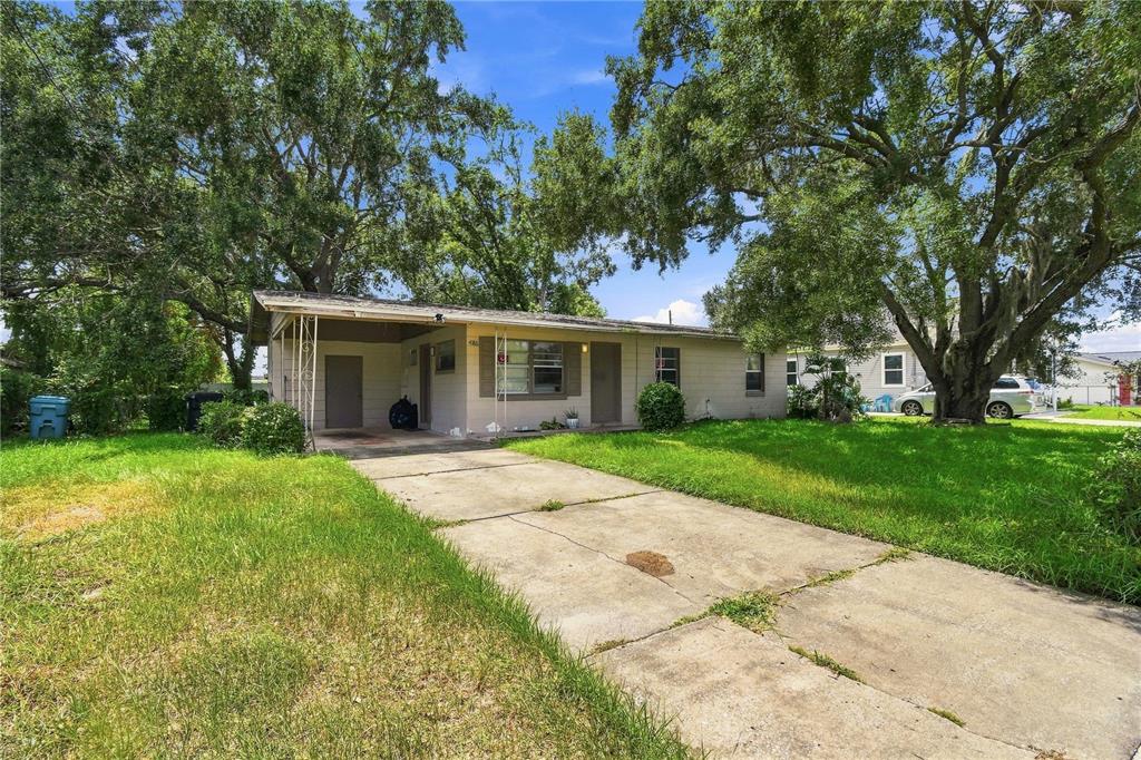 A single-story house with a concrete driveway, a carport, and large trees in the yard — 4186 CEPEDA STREET, ORLANDO, FL