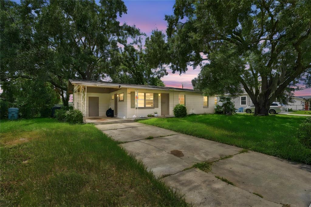 A single-story house with a concrete driveway, a carport, and large trees in the yard — 4186 CEPEDA STREET, ORLANDO, FL