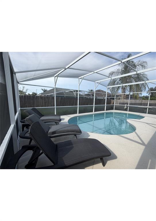 A swimming pool with lounge chairs inside a screened-in patio enclosure — 314 ALLISON AVENUE, DAVENPORT, FL