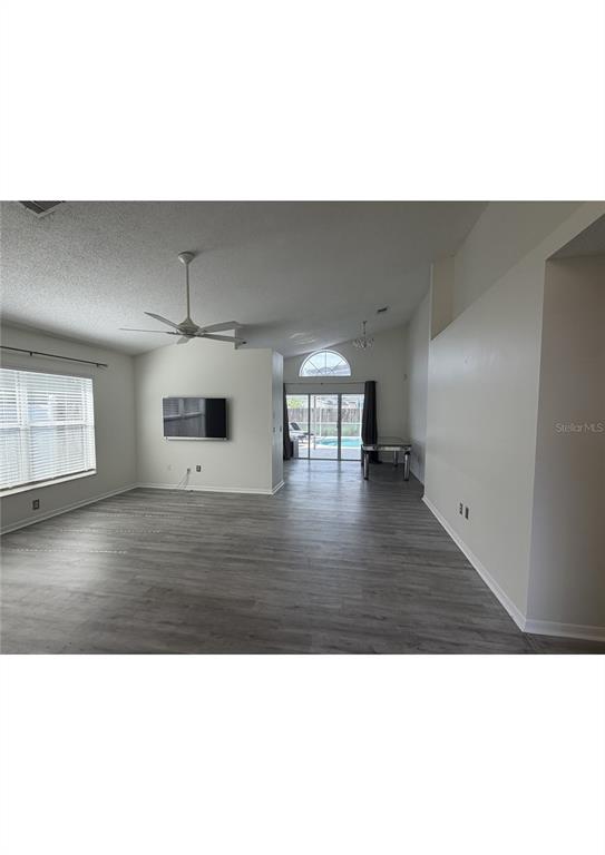 A spacious living area features light gray wood-look flooring, a ceiling fan, and sliding glass doors — 314 ALLISON AVENUE, DAVENPORT, FL