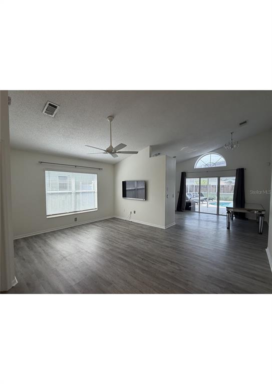 A living room with gray wood-look flooring, a ceiling fan, and sliding glass patio doors — 314 ALLISON AVENUE, DAVENPORT, FL