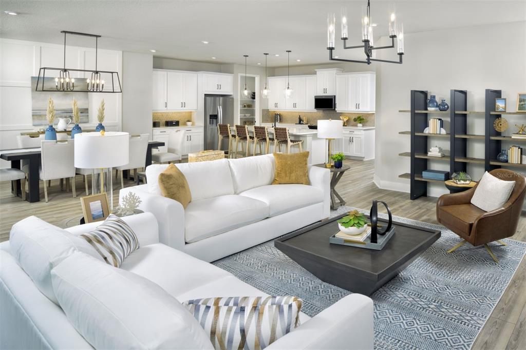 An open-concept living and dining area features white sofas, a dark coffee table, and kitchen — 35507 PEAK WILLOW TRACE, DADE CITY, FL