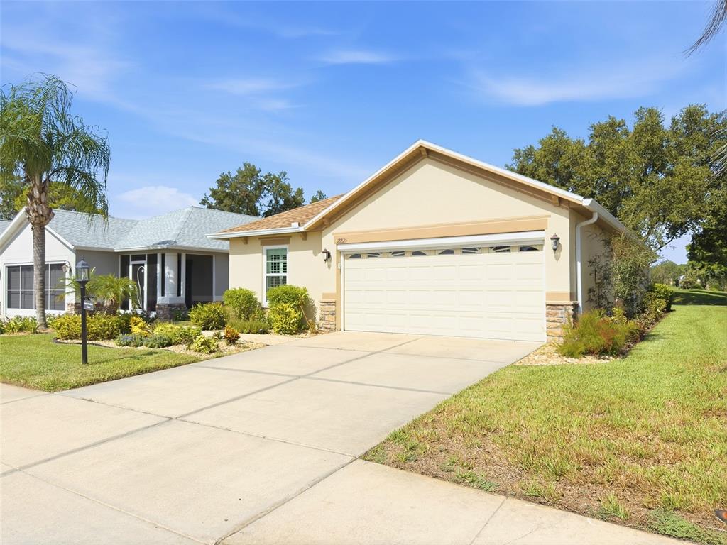 A beige single-story house with a two-car garage and a concrete driveway — 18825 WATER LILY LANE, HUDSON, FL