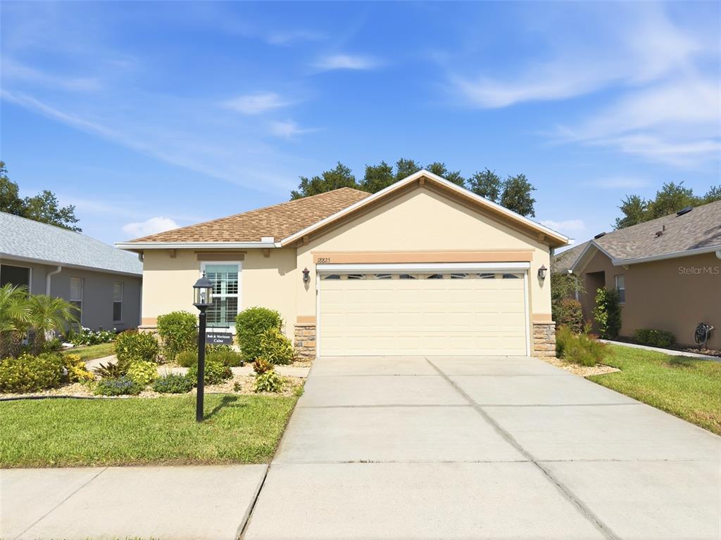 A single-story house with a beige stucco exterior and a two-car garage — 18825 WATER LILY LANE, HUDSON, FL