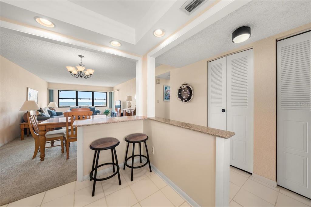 A kitchen breakfast bar with two stools overlooks a dining area and living room — 1230 GULF BOULEVARD UNIT 403, CLEARWATER BEACH, FL