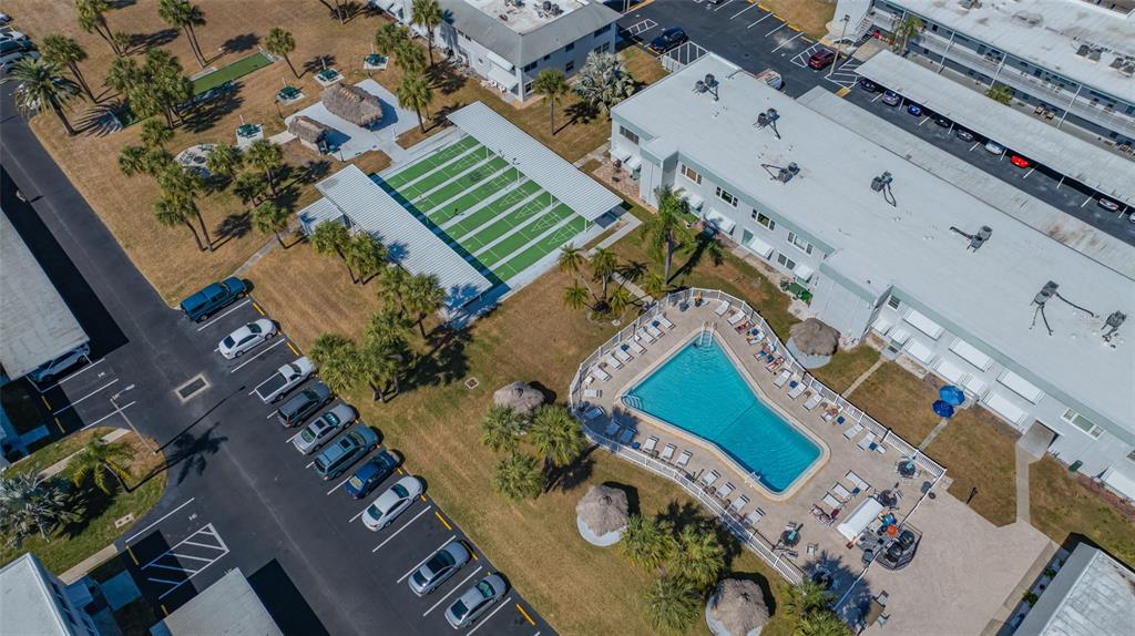 An aerial view shows a swimming pool, a covered sports court, and a parking lot — 5217 81ST STREET N UNIT 16, ST PETERSBURG, FL